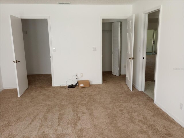 unfurnished bedroom with a walk in closet, a closet, and carpet