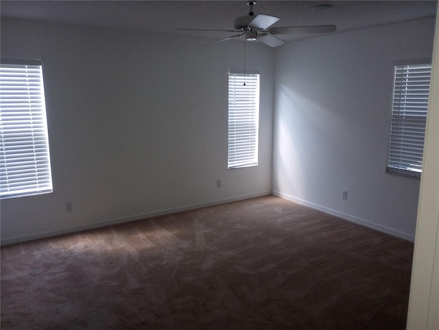 empty room with ceiling fan and dark colored carpet