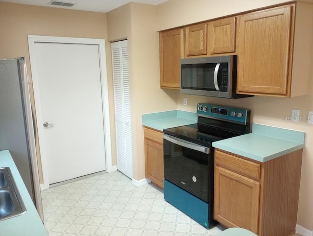 kitchen with light tile floors, sink, and range with electric stovetop