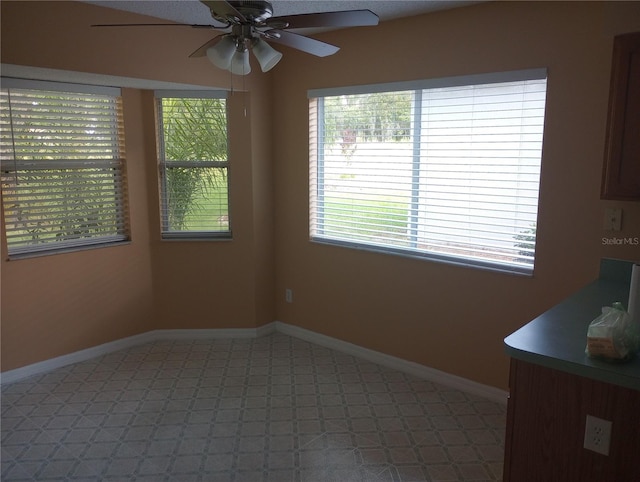 unfurnished dining area with baseboards, light floors, and ceiling fan