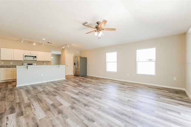 unfurnished living room with rail lighting, light hardwood / wood-style flooring, and ceiling fan