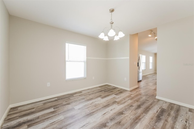 unfurnished room with a notable chandelier and hardwood / wood-style floors