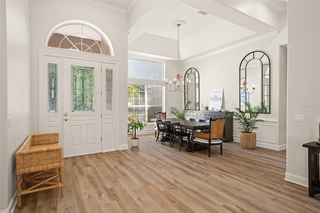 dining room with crown molding, a towering ceiling, a notable chandelier, and light wood-type flooring