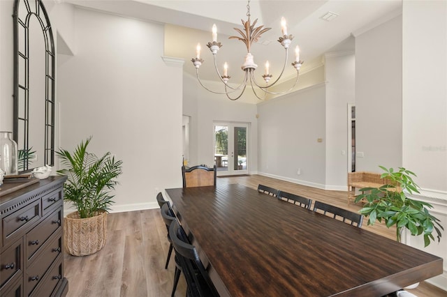 dining room featuring a chandelier, french doors, light hardwood / wood-style floors, and crown molding