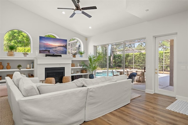 living room featuring wood-type flooring, a premium fireplace, plenty of natural light, and ceiling fan