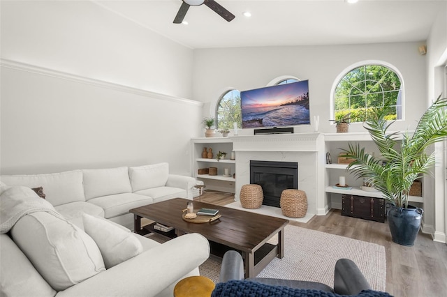 living room with ceiling fan, light hardwood / wood-style flooring, a high end fireplace, and lofted ceiling