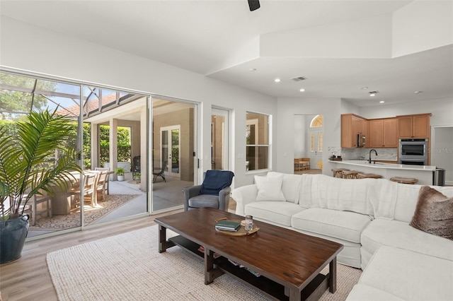 living room with french doors, sink, and light hardwood / wood-style flooring