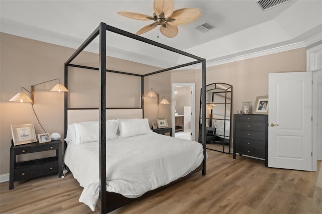 bedroom featuring connected bathroom, hardwood / wood-style flooring, ceiling fan, and crown molding