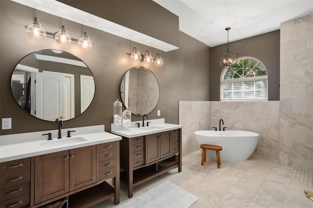 bathroom with a notable chandelier, a bathtub, tile walls, and vanity