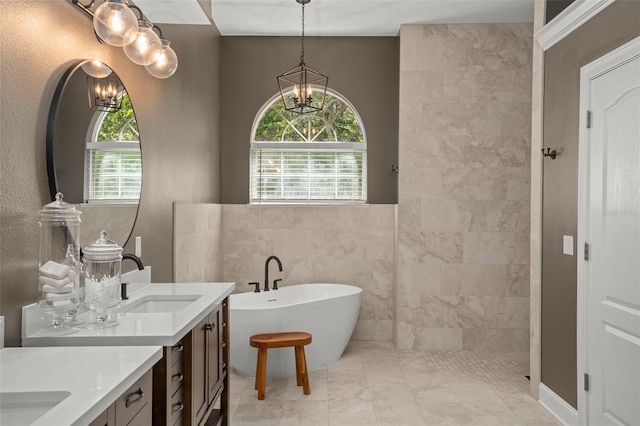 bathroom with a washtub, vanity, tile walls, and a notable chandelier