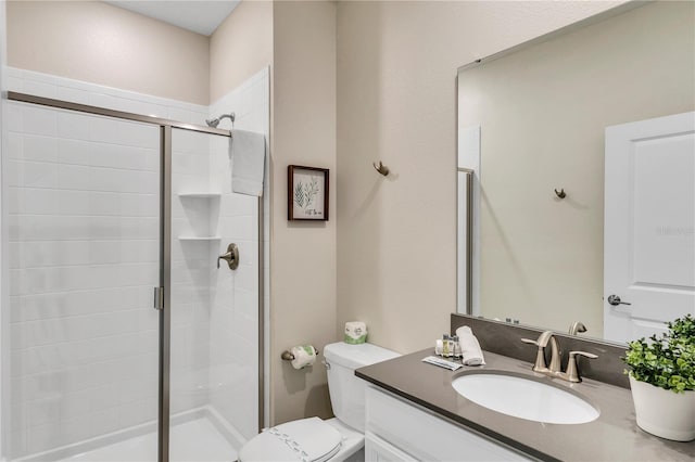 bathroom with a shower with shower door, vanity with extensive cabinet space, and toilet