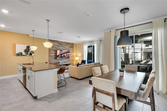 kitchen with light tile floors, stainless steel dishwasher, white cabinetry, and sink