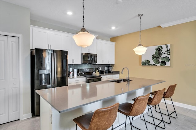 kitchen with decorative light fixtures, backsplash, a center island with sink, black appliances, and white cabinets