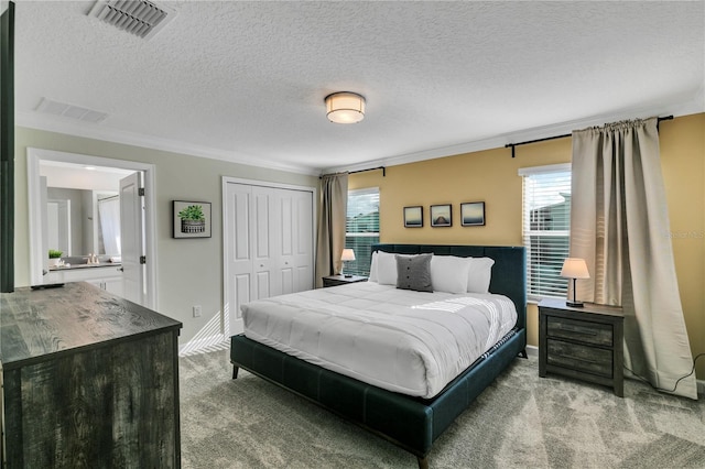 bedroom with a closet, a textured ceiling, crown molding, and carpet flooring