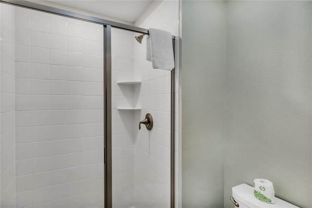 bathroom with a shower with door and toilet