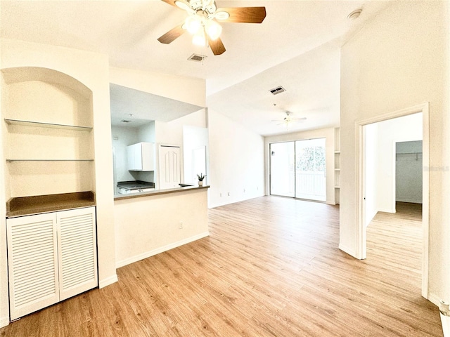 unfurnished living room with a textured ceiling, ceiling fan, vaulted ceiling, and light hardwood / wood-style floors