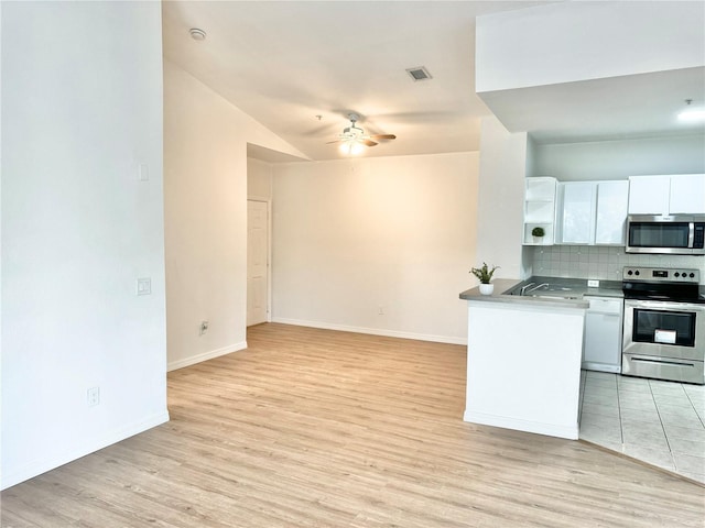 kitchen featuring light hardwood / wood-style flooring, stainless steel appliances, decorative backsplash, ceiling fan, and white cabinets