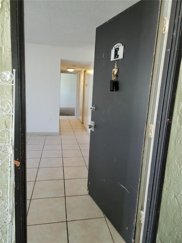 hallway with light tile patterned floors and a textured ceiling