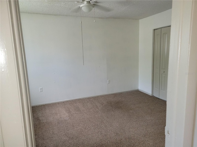 empty room with carpet flooring, ceiling fan, and a textured ceiling