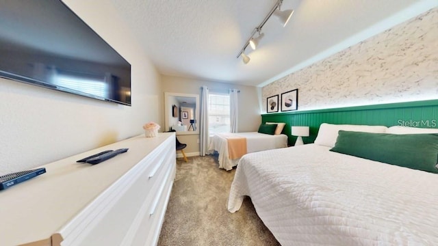 carpeted bedroom featuring a textured ceiling and track lighting