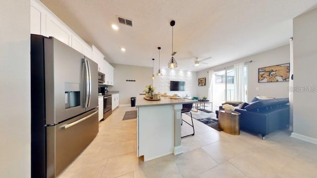 kitchen featuring ceiling fan, a kitchen island, white cabinets, stainless steel appliances, and a kitchen breakfast bar