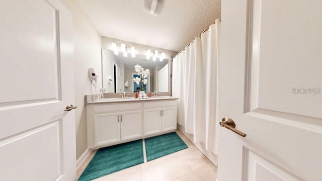 bathroom with a textured ceiling, tile floors, and vanity with extensive cabinet space