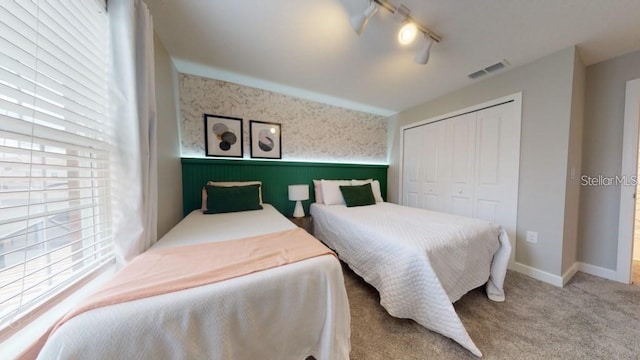 carpeted bedroom with rail lighting and a closet