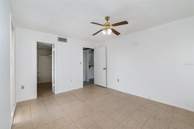 unfurnished bedroom featuring a spacious closet, a closet, ceiling fan, and a textured ceiling