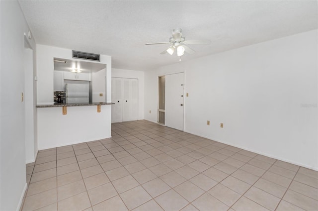 unfurnished living room featuring ceiling fan and light tile patterned flooring