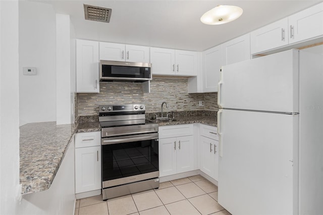 kitchen featuring appliances with stainless steel finishes, sink, dark stone counters, and white cabinetry