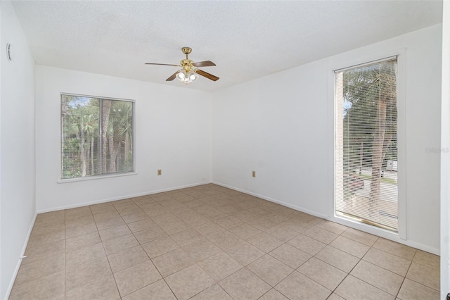 tiled spare room featuring ceiling fan, a textured ceiling, and plenty of natural light