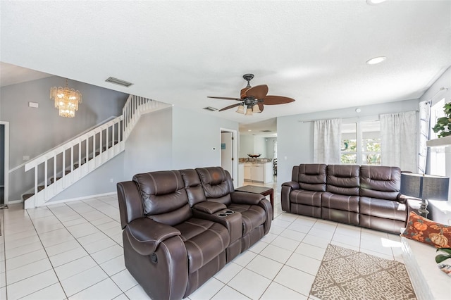 living room with ceiling fan with notable chandelier, a textured ceiling, and light tile floors