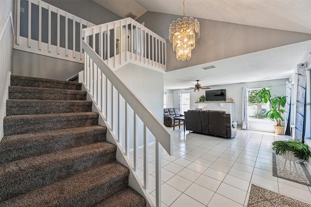 staircase featuring ceiling fan with notable chandelier, a textured ceiling, high vaulted ceiling, and light tile floors