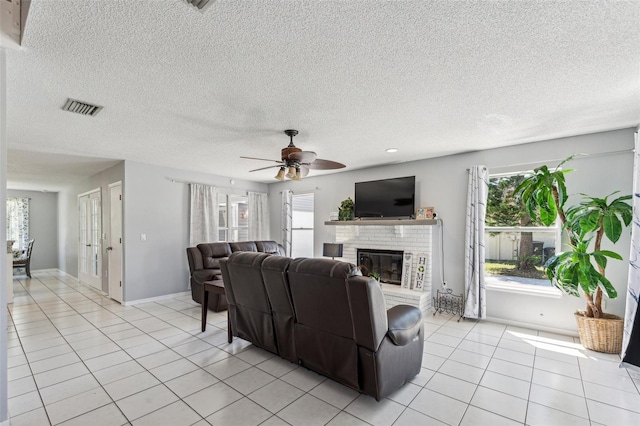 tiled living room featuring plenty of natural light, a fireplace, and a textured ceiling