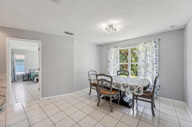 dining area featuring a textured ceiling, a wealth of natural light, and light tile floors