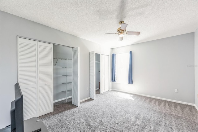 unfurnished bedroom featuring two closets, ceiling fan, carpet, and a textured ceiling