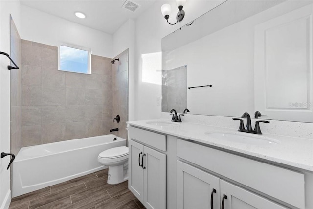 full bathroom with tiled shower / bath combo, vanity, and toilet