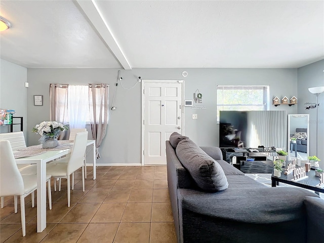 living room with tile patterned flooring, baseboards, and beamed ceiling