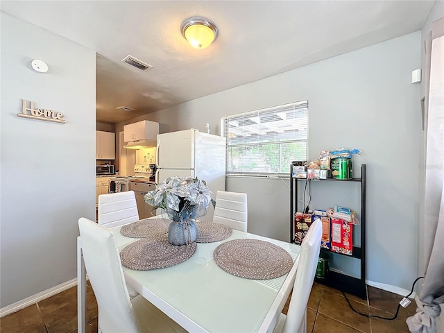 dining room featuring dark tile patterned floors, visible vents, and baseboards