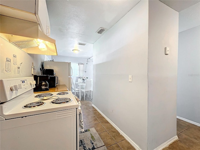 kitchen with white appliances, light tile patterned floors, visible vents, and light countertops