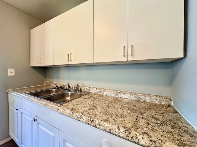 kitchen featuring white cabinetry and a sink