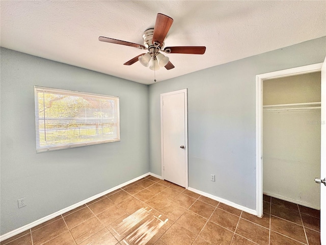 unfurnished bedroom with a textured ceiling, baseboards, a closet, and tile patterned floors