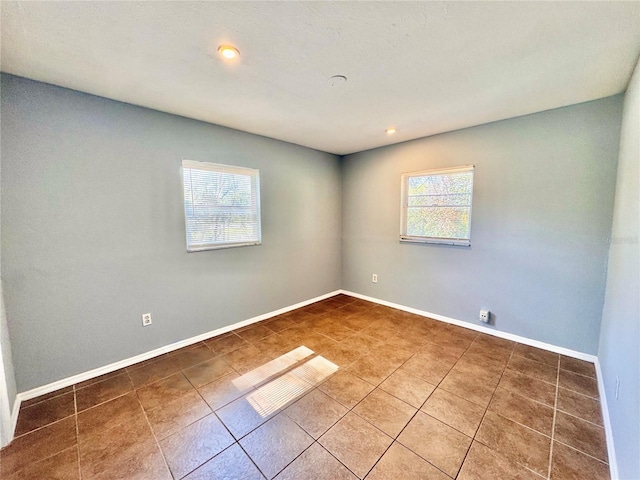 empty room featuring recessed lighting, baseboards, and tile patterned floors