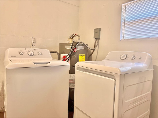 laundry room with water heater, laundry area, washing machine and dryer, and concrete block wall