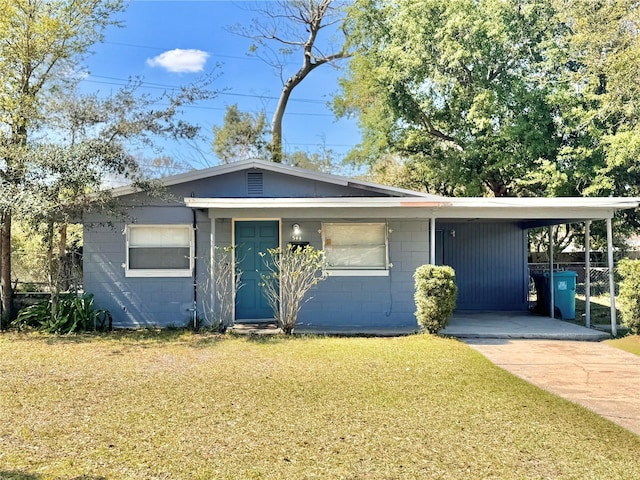 view of front of house with driveway, an attached carport, a front yard, and concrete block siding