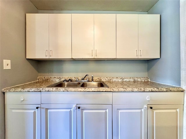 kitchen featuring white cabinetry, light countertops, and a sink