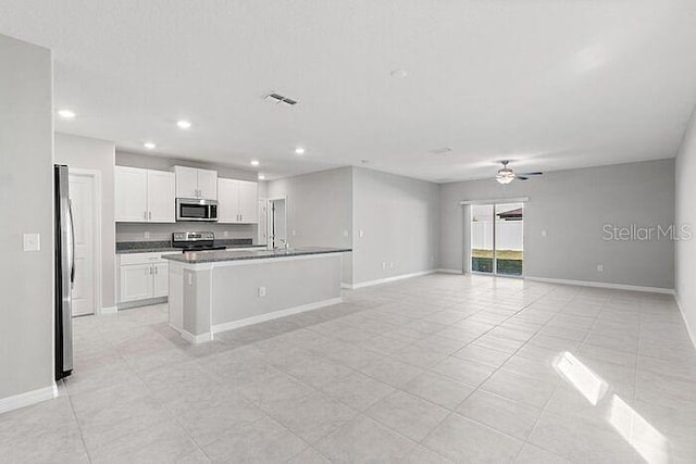 kitchen with ceiling fan, stainless steel appliances, an island with sink, white cabinets, and light tile floors