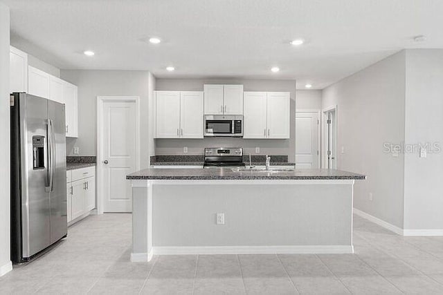 kitchen featuring stainless steel appliances, light tile flooring, and an island with sink