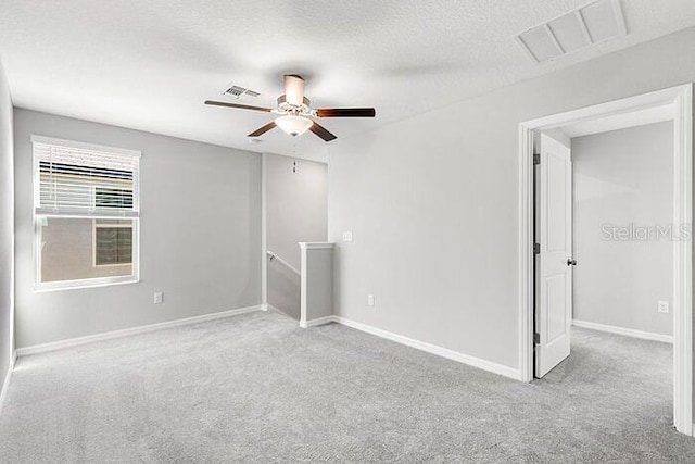 carpeted spare room with ceiling fan and a textured ceiling