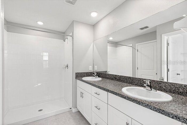 bathroom with tile floors, double vanity, and a tile shower